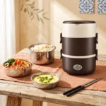 Boîte lunch électrique chauffante 3 étages brune sur une table, avec ses bols inox remplis