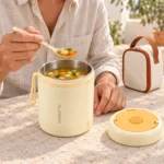 Homme mangeant une soupe chaude dans son thermos chauffant USB, sac à côté