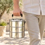 Lunch box inox grande capacité avec poignée portée lors d’un déjeuner