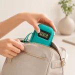 Sac isotherme médicaments turquoise glissé dans un sac à main beige, afficheur de température visible