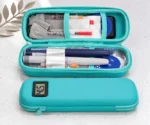 Sac isotherme médicaments turquoise ouvert, stylos injecteurs et petits accessoires rangés dans les deux compartiments